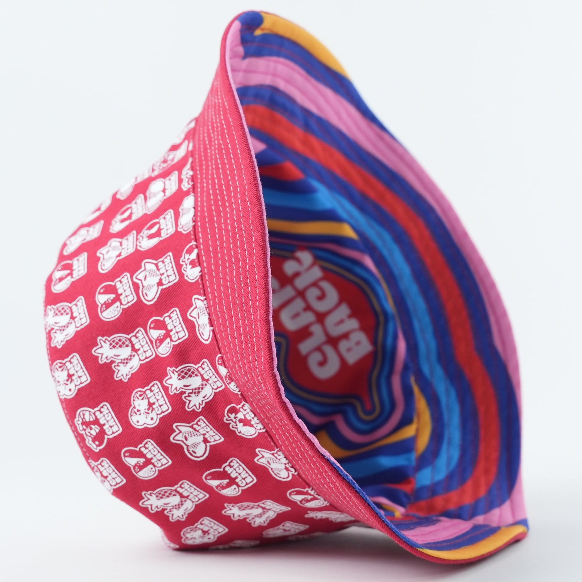 A colorful bucket hat shown on a clean white background, with a pink exterior covered in white cartoon characters and a striped interior in shades of blue, red, yellow, and purple.