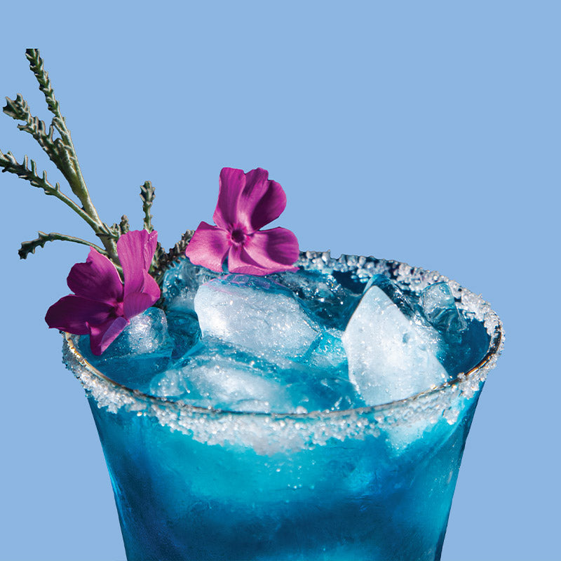ClapBack Blue Rizzler cocktail with ice and purple flowers against a clear blue background