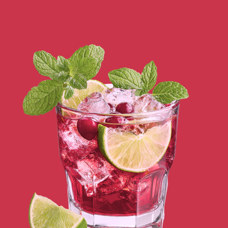 ClapBack Cry Baby Cranberry Wine Cocktail with cranberries, lime slices, and mint leaves on a red background