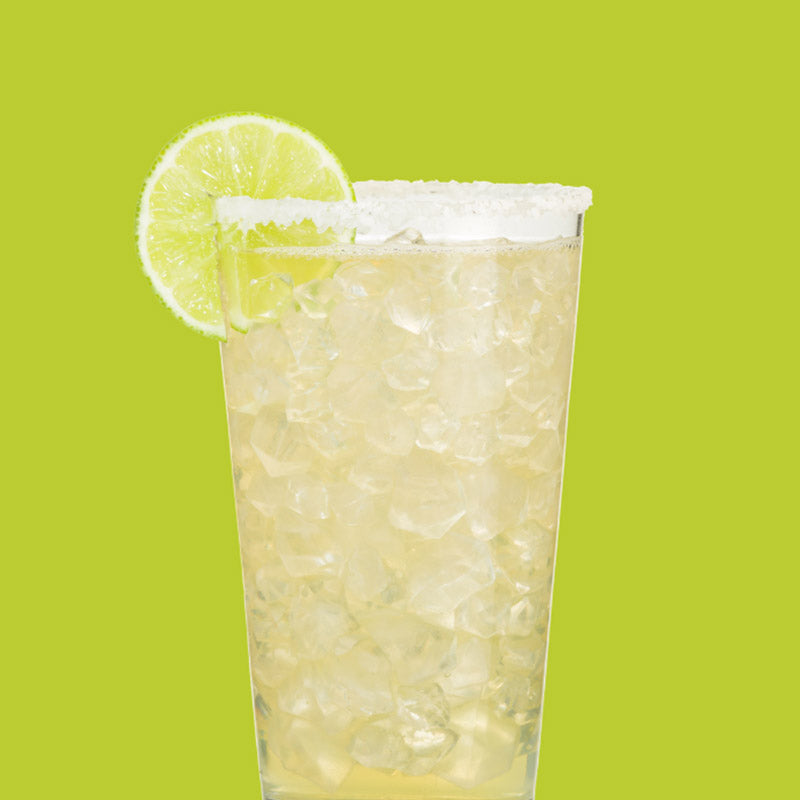 Glass of ClapBack Lil Limeade drink with a lime wedge on a green background