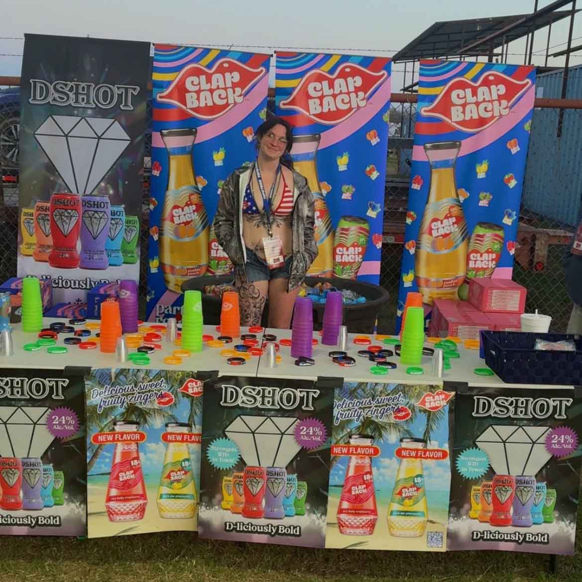 Person standing behind a colorful product display with 'Clap Back' and 'Dshot' branding.