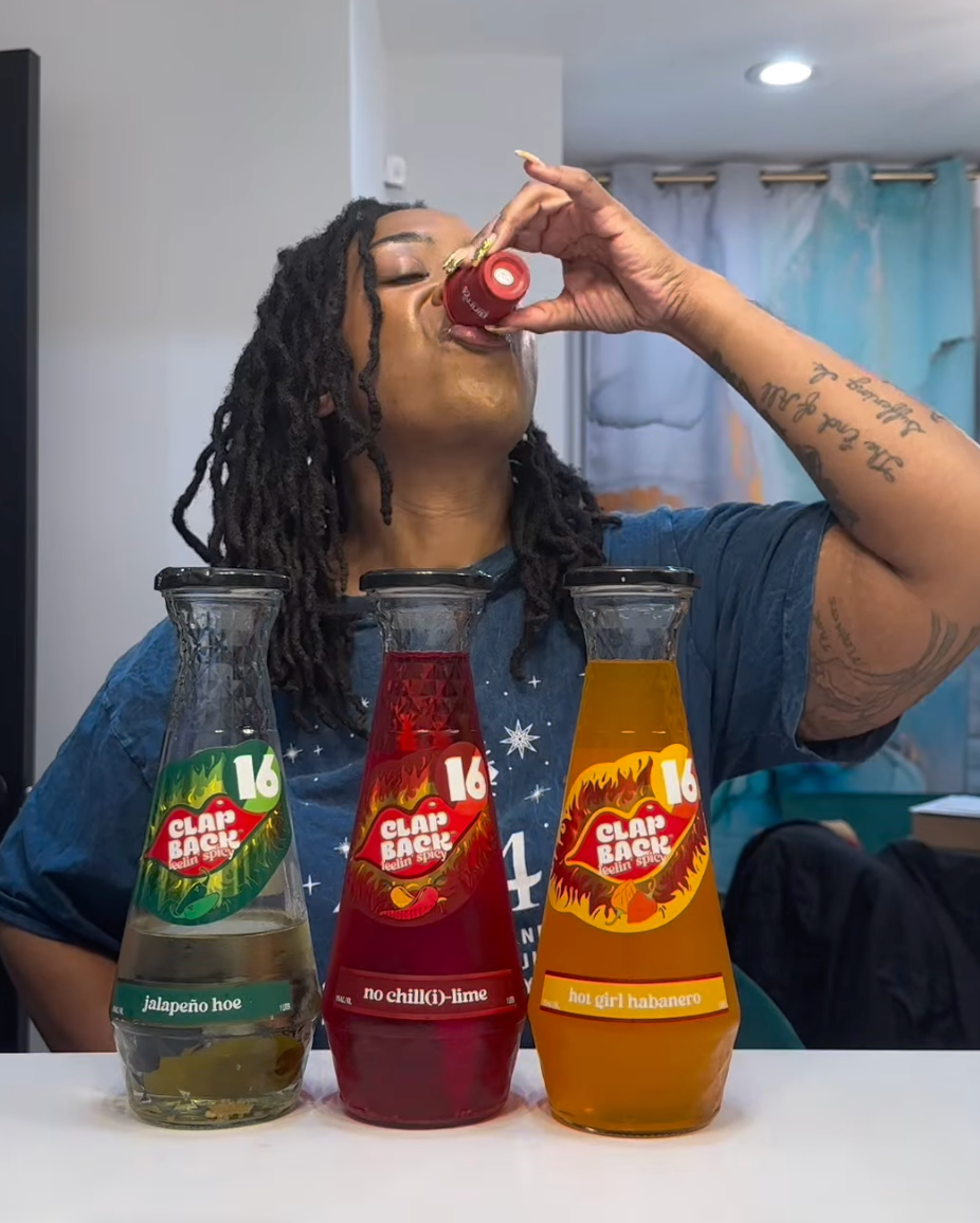 Person drinking from a bottle with three other bottles of different flavors on a table.