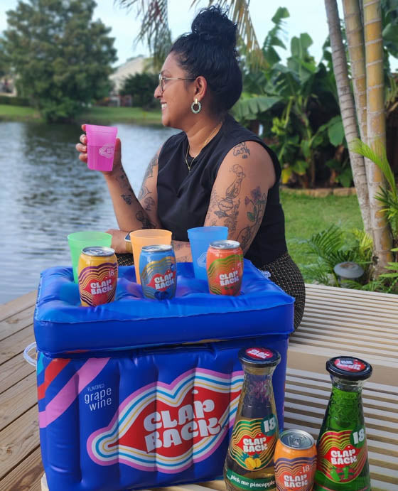 Person sitting by a waterfront with a cooler full of clapback